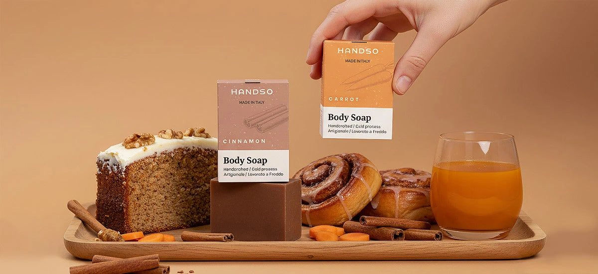 Handso body soap bars on a tray with cinnamon rolls, a cake, and a glass of juice against a beige background
